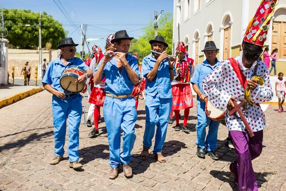 Músicos tradicionais tocando pífanos e tambor em manifestação cultural popular de rua
