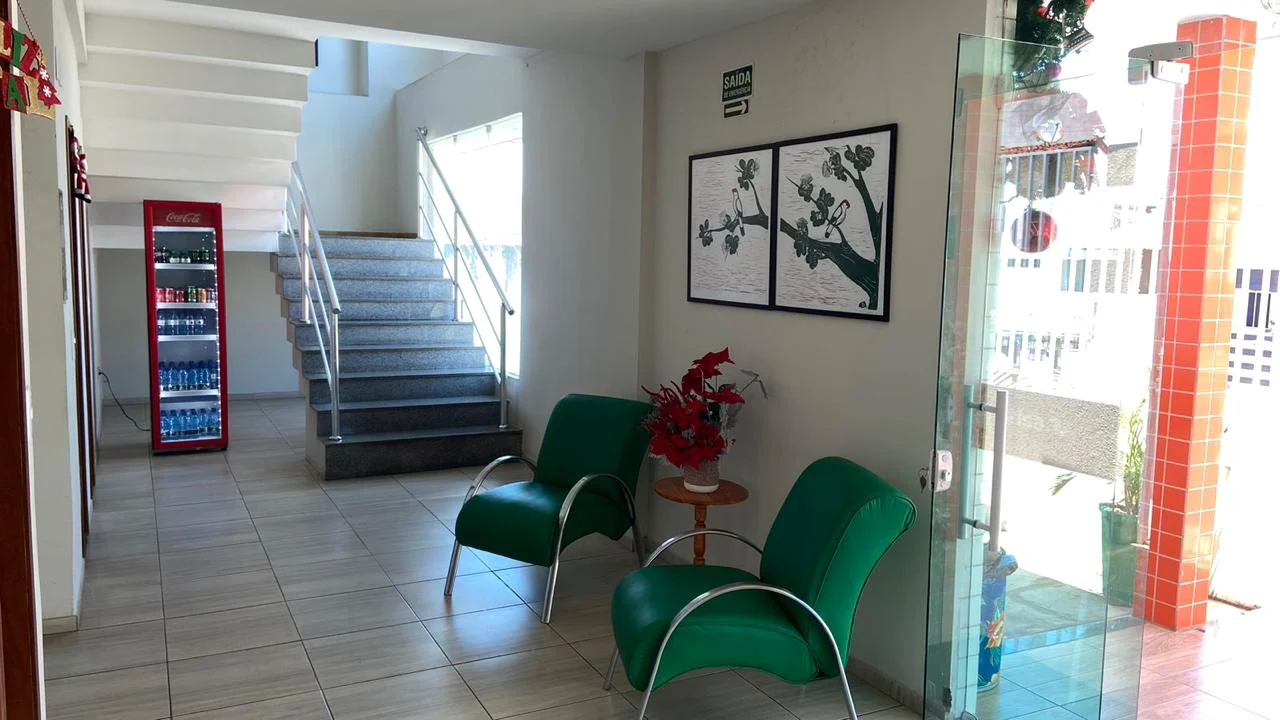 Hall de entrada do Brisa Hotel com poltronas verdes e escadaria