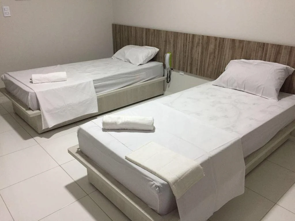 Acomodação com duas camas de solteiro e enxoval branco