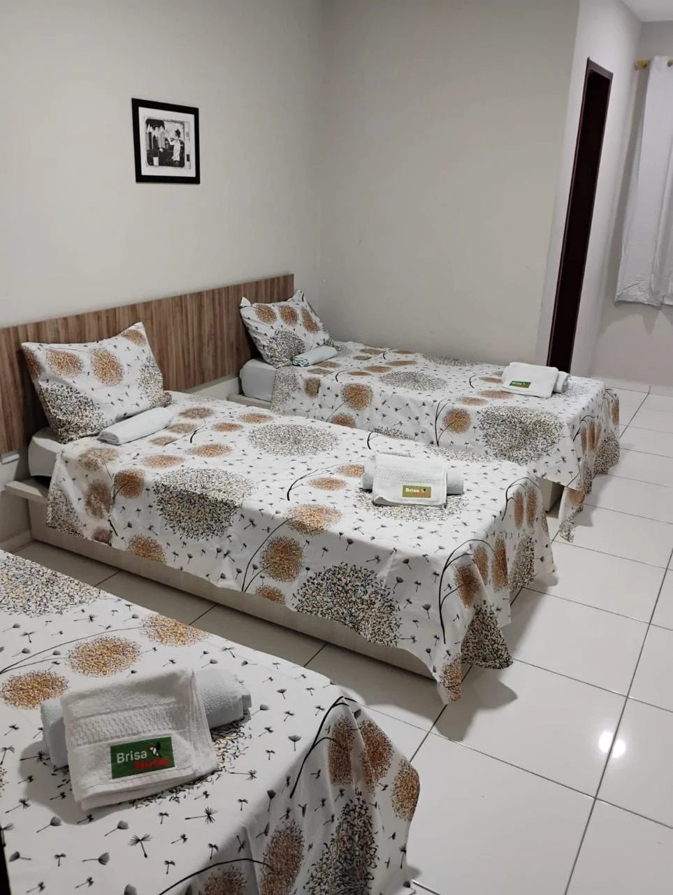 Detalhe de acomodação tripla com toalhas dobradas e cabeceira amadeirada